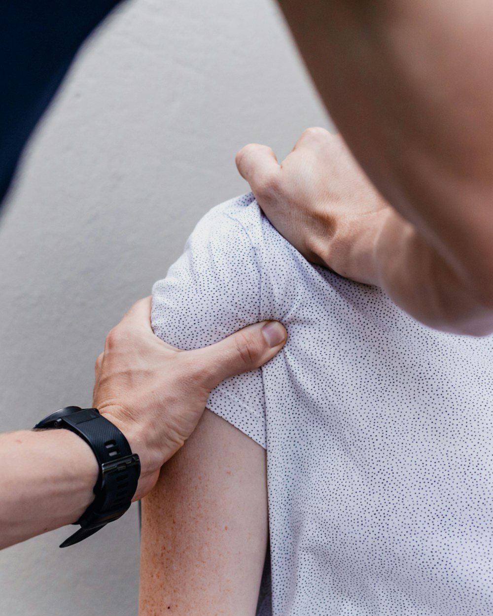 Coach assessing a client's shoulder by hand during an in-person shoulder rehab assessment in Edmonton